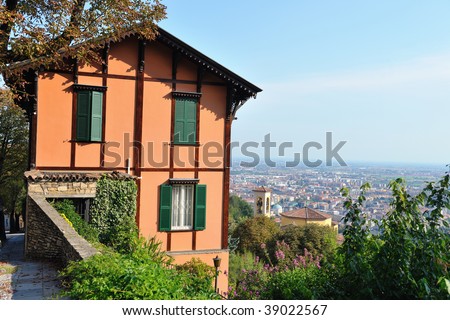 Pretty apricot orange coloured northern Italian villa on a hill overlooking Bergamo, Lombardy, Italy and the flat Po Valley beyond