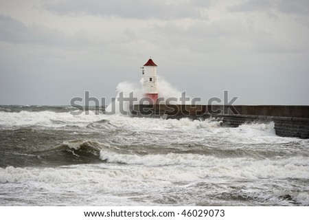Wave breaking over Berwick upon Tweed lighthouse, Northumberland, England, UK, on a stormy winter day