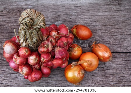 Organic red and orange color of onions on wooden background with free text space.