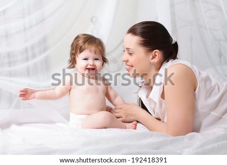Mom and baby in love, smiling, playing in bed