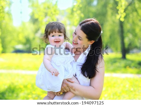 Happy mom and baby in the park in the summer, having fun, sunny day