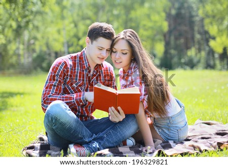 Beautiful young teen couple reading a book in a city park, reading, learning, students - concept