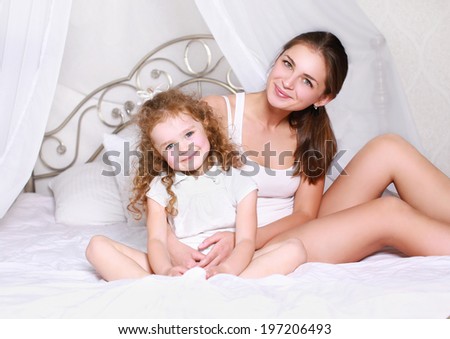 Lovely happy mom and daughter in bed bedtime