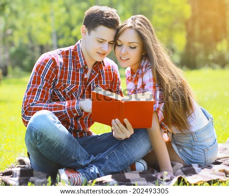 Portrait beautiful young man and girl reading a book in a city park, reading, learning, students - concept