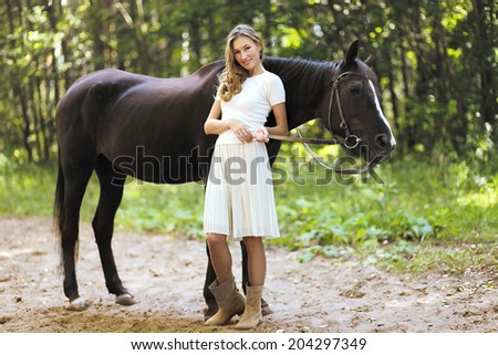 Happy woman smiling and horse in forest in warm summer day