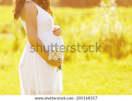 Pregnancy lovely woman with flowers in summer sunny day, tender moment