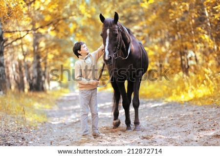 Autumn season happy teenager boy and horse walking in forest - stock photo Autumn season happy teenager boy and horse walking in forest - stock photo