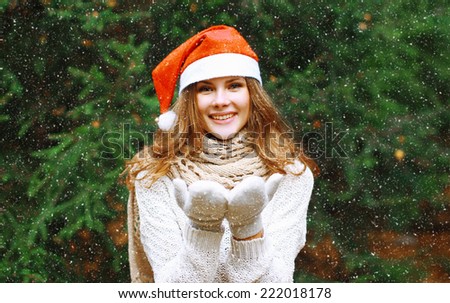 Christmas and people concept - happy young girl in winter hat near tree having fun outdoors