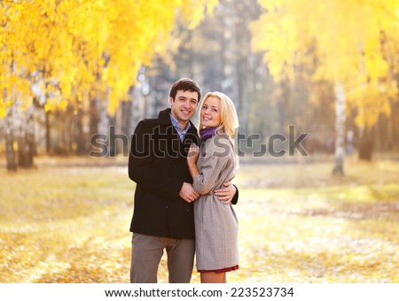 Autumn, love, relationships and people concept - lovely young couple walking in sunny autumn park