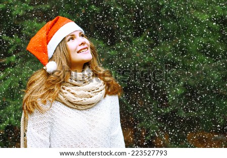 Christmas and people concept - happy girl in winter hat near tree