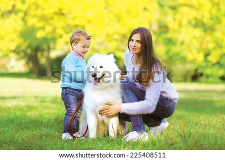 Family, leisure and people concept - mother and child walking with dog in the park