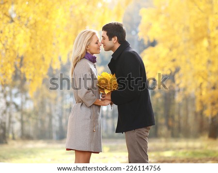 Autumn, love, relationships and people concept - pretty young couple kissing in autumn park