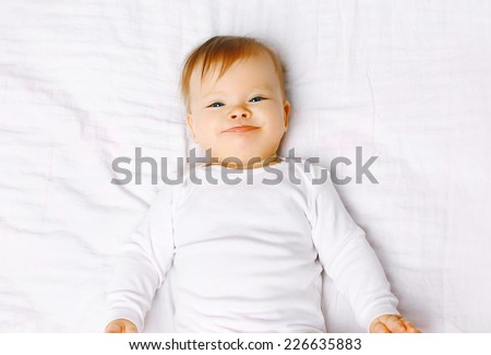 Portrait positive baby lying on the bed, top view