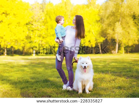 Family, leisure and people concept - mother and child having fun walking with dog in the park