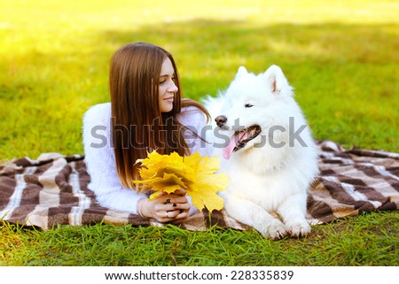 Portrait happy pretty woman and white Samoyed dog on the plaid outdoors