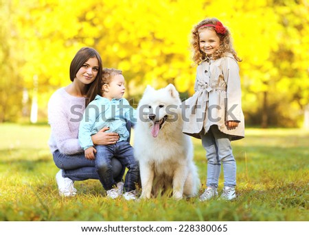Family portrait, pretty young mother and children walks with dog outdoors in the park