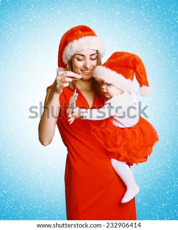 Christmas and people concept - happy mother playing with baby against the snowflakes