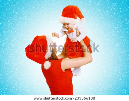 Christmas and people concept - positive happy mother and baby having fun against the snowflakes