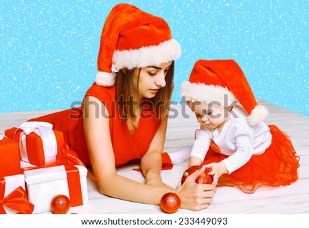 Christmas and people concept - mother and baby playing with balls against the snowflakes