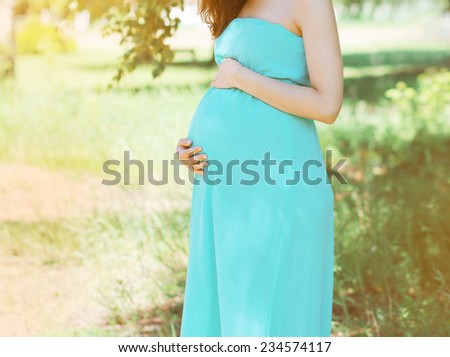 Lovely pregnant woman in dress outdoors in summer day on nature