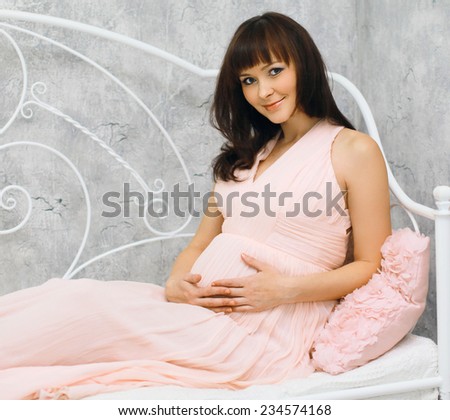 Lovely young pregnant woman on the bed at home