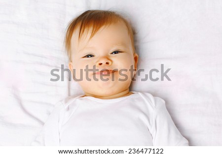 Closeup portrait cute positive baby on the bed, top view