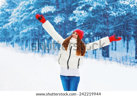 Winter and people concept - pretty woman rejoices winter weather in snowy day