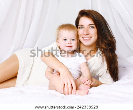 Happy mom and baby on the bed at home