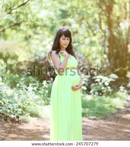 Beautiful pregnant woman in dress outdoors on nature