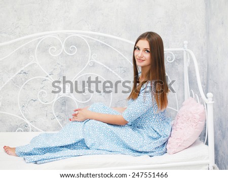Lovely young woman in the spring dress in white room