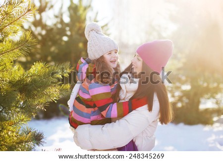 Winter and people concept - mother and child having fun playing in sunny winter day