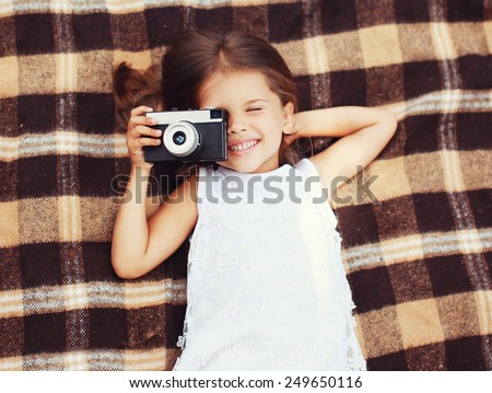 Funny child shooting vintage old retro camera and having fun on the plaid, top view