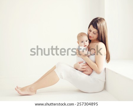 Soft comfort photo young mother with baby at home in white room near window