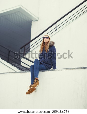 Urban stylish hipster woman outdoors sitting in the city