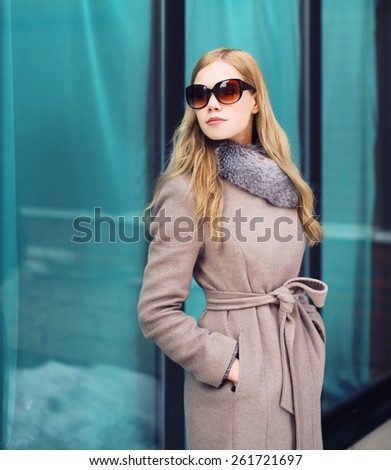 Beautiful elegant woman dressed a coat and sunglasses outdoors in the city