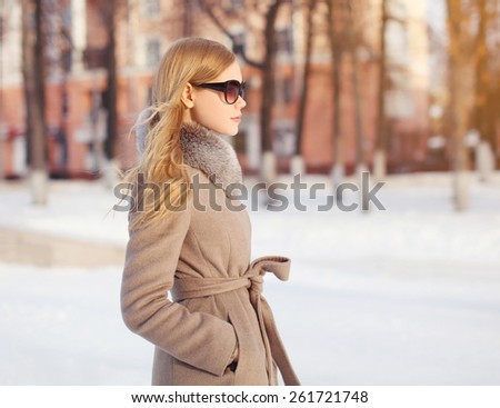 Outdoor portrait of profile beautiful elegant woman dressed a coat and sunglasses in the park