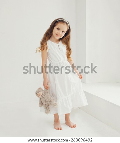 Cute little girl with teddy bear at home in white room