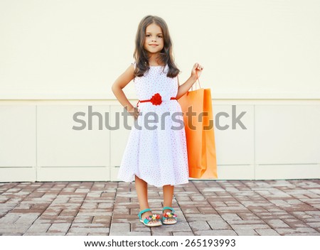 Portrait of beautiful little girl in white dress with shopping bag