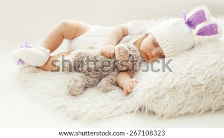 Baby comfort! Sweet infant at home sleeping with teddy bear on the fur