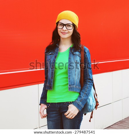 Portrait of pretty girl in glasses wearing a bright casual clothes against the colorful red wall