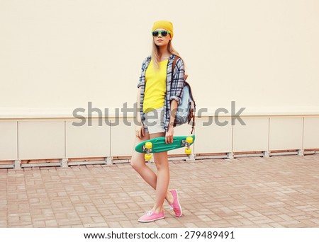 Fashion summer hipster cool woman in sunglasses and colorful clothes with skateboard outdoors