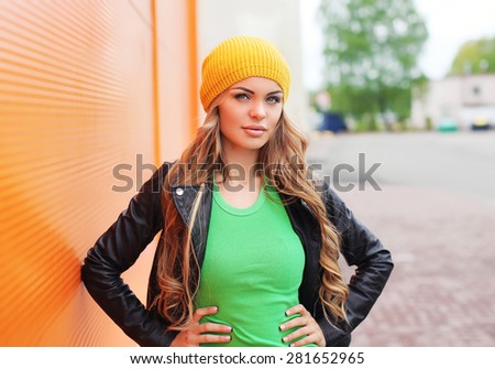 Outdoor fashion portrait of beautiful blonde woman wearing a black rock leather jacket and hat in the city