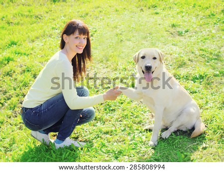 Happy owner woman and labrador retriever dog trains on the grass in summer day