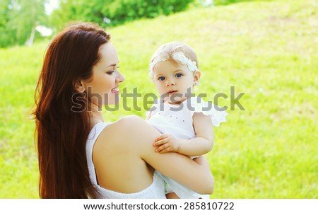 Happy loving mother and baby together outdoors in sunny summer day