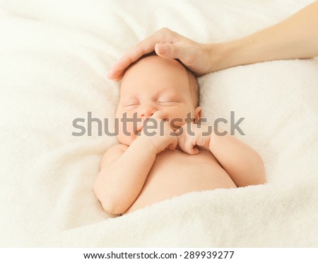 Portrait cute baby sleeping on the bed under blanket and affectionate hand of mother