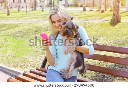 Young smiling girl owner with yorkshire terrier dog sitting in the park