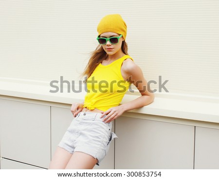 Portrait of fashion pretty woman in sunglasses and colorful yellow clothes outdoors