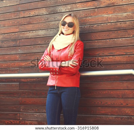 Fashion beautiful smiling woman wearing a red leather jacket and scarf in the city