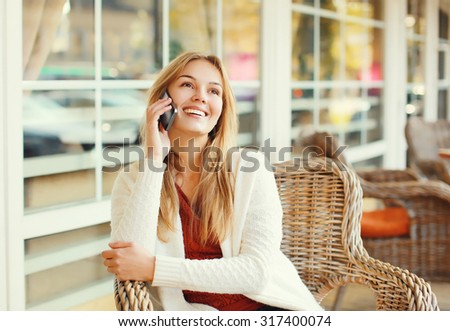 Happy pretty smiling woman talking on smartphone in cafe