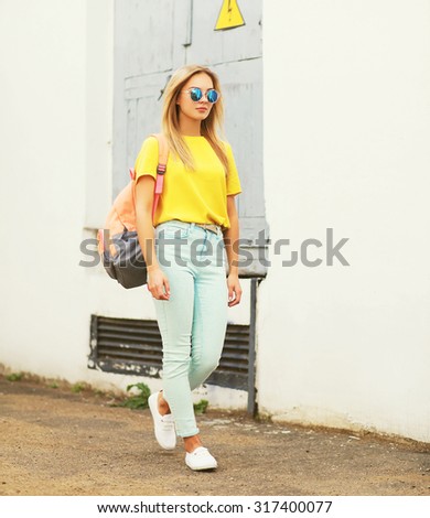 Fashion pretty young woman wearing a sunglasses and t-shirt with backpack walking in the city